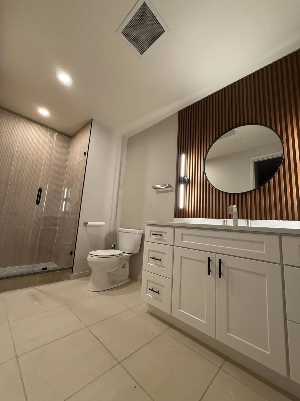 Wood slat accent wall, round mirror & white vanity